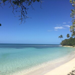 A beach with clear turquoise water, white sand, and palm trees. - House with amazing architecture with private pool and full A/C.  (Cabo Rojo)