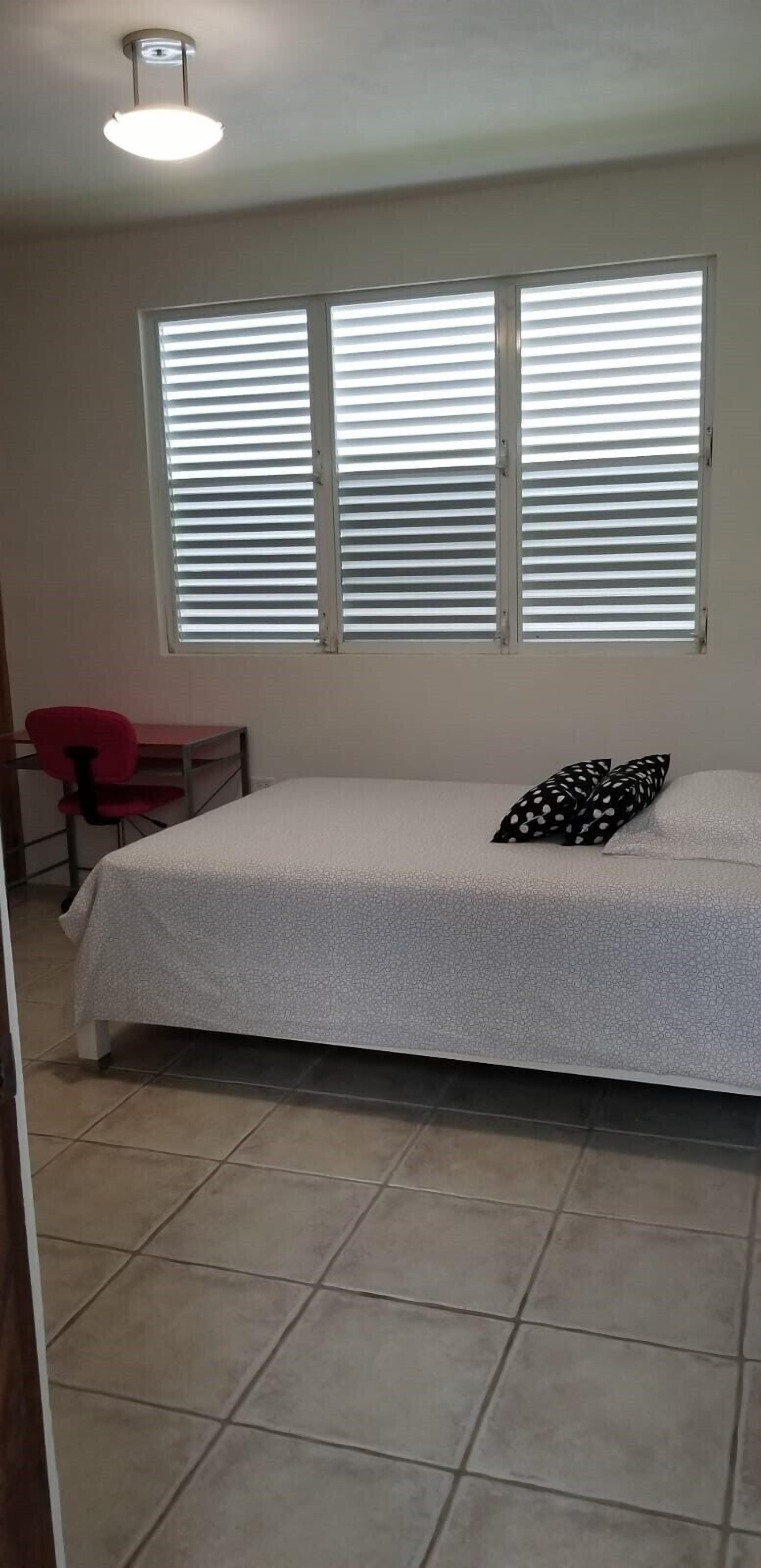 Un dormitorio con cama, escritorio y silla.