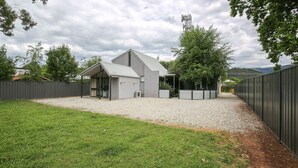A modern building with a sloped roof, a covered patio area, and a gravel driveway. - ALLAMBIE COTTAGES - VILLA 3: Bright (Bright)
