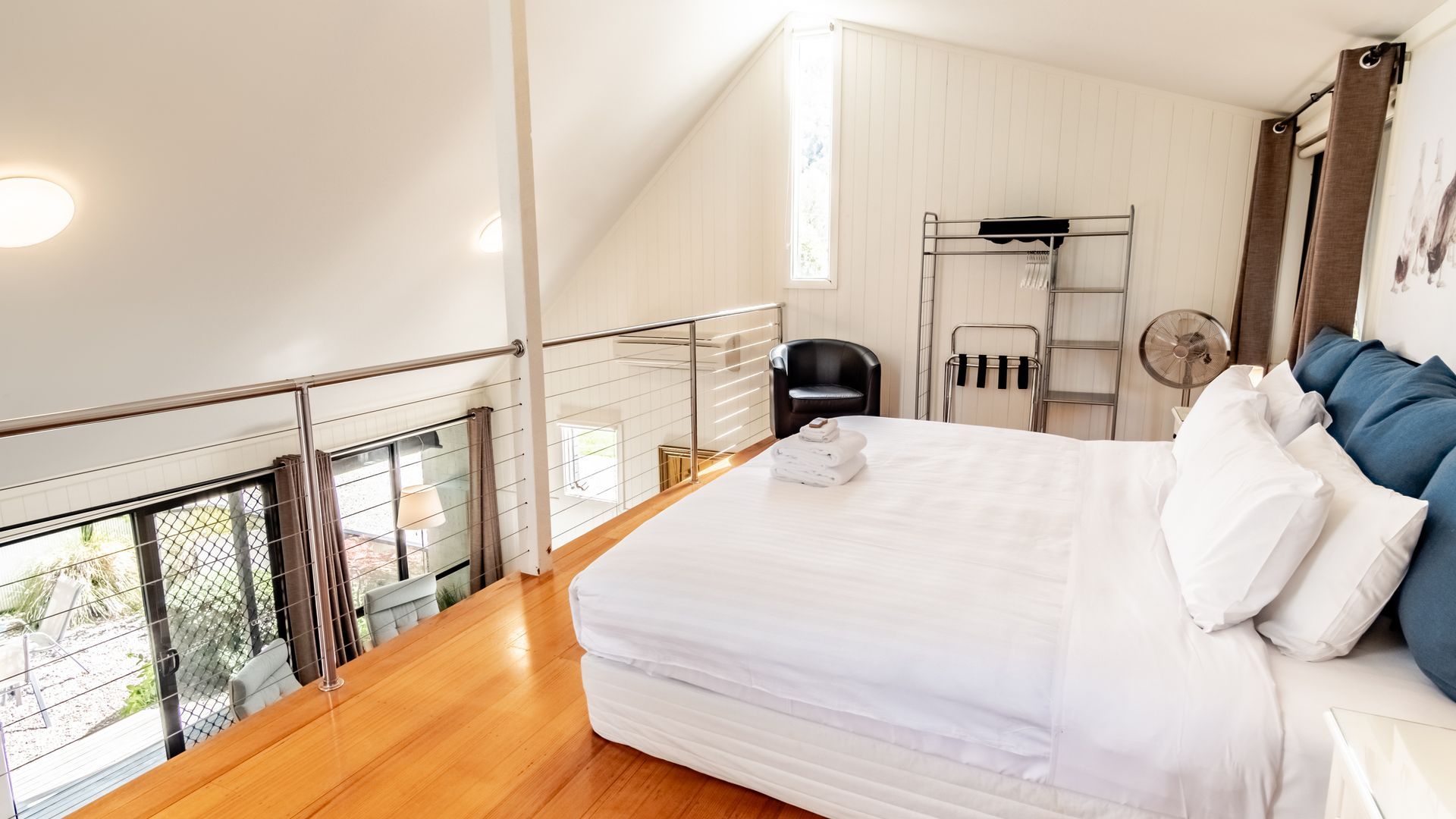 A bedroom with a bed, a chair, a fan, and a window.
