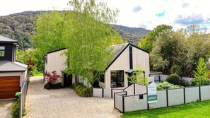 A modern two-story building with a gravel driveway and a fenced garden area.
