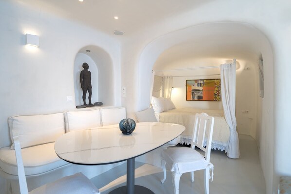 Une pièce au décor minimaliste, avec un canapé blanc, une table ronde et un lit à baldaquin.