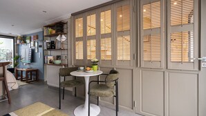 A dining area with a round table, two upholstered chairs, and a small side table. - Stunning Studio With Private Patio In Charming Gated Street (Neuilly-Sur-Seine)