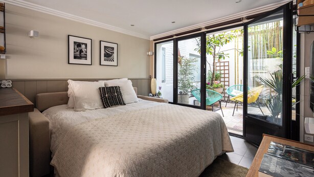A bedroom with a bed, a desk, and a view of the outside. - Stunning Studio With Private Patio In Charming Gated Street (Neuilly-Sur-Seine)