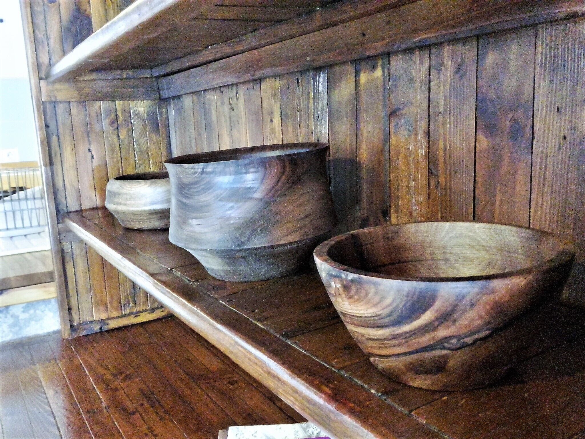 A wooden shelf with three pottery bowls.