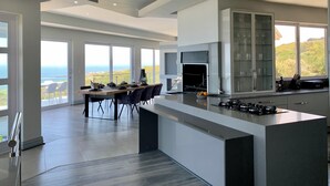 A modern kitchen with a large island, a dining area with a view, and a fireplace.