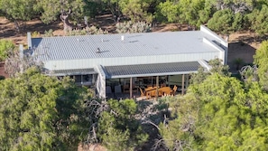 A modern house with a flat roof, large windows, and a covered outdoor seating area.
