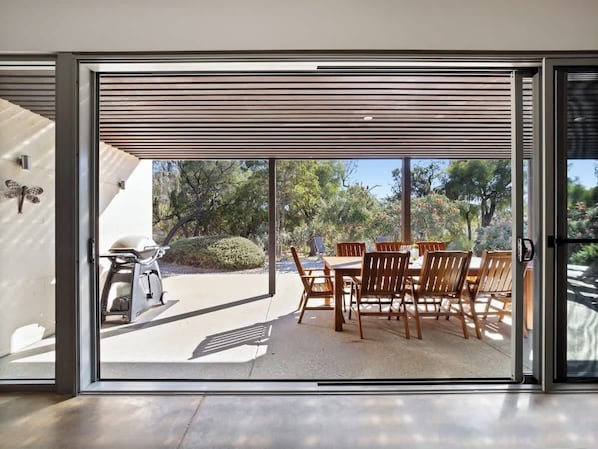 A sliding glass door leading to an outdoor patio with a barbecue grill and wooden dining table and chairs.