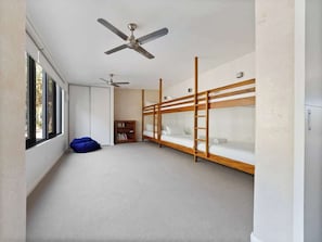 A room with bunk beds, a ceiling fan, a bookshelf, and a bean bag chair.
