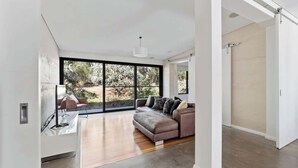 Een modern interieur met een bank, een salontafel en een groot raam met uitzicht op groen.