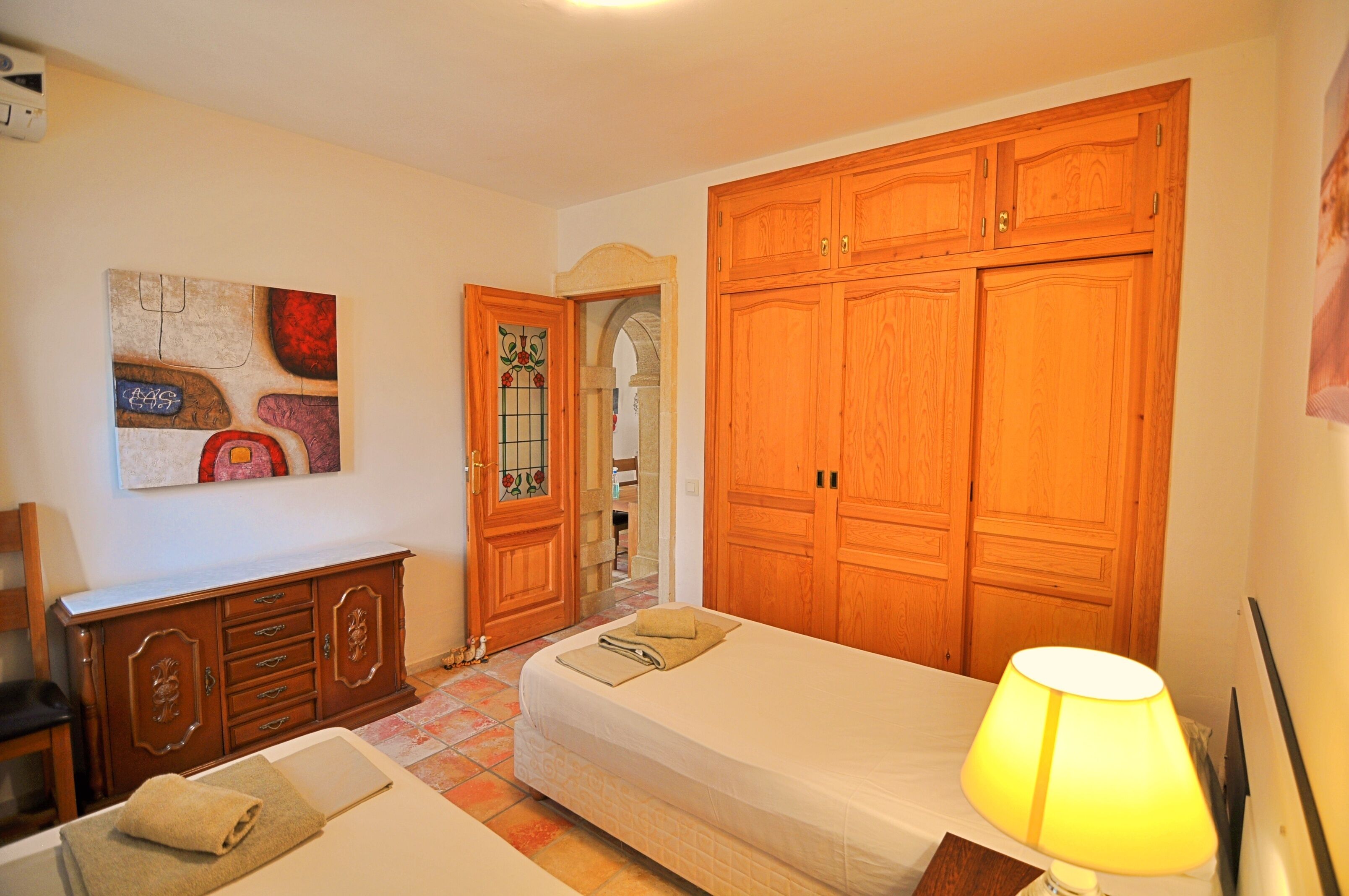 Un dormitorio con una cama, un armario de madera, un tocador y un cuadro en la pared.