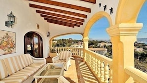 Ein Balkon mit einer Couch, einem kleinen Tisch und Blick auf die Landschaft.