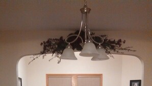 Ein Esszimmer mit Holztisch, Stühlen, einer Blumenvase, einer Chandelierleuchtre und einem Ledersofa.
