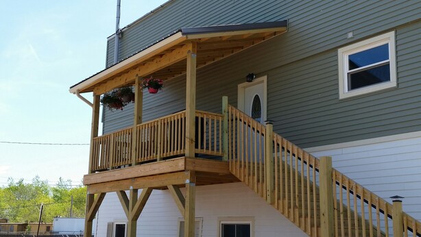 Ein zweistöckiges Haus mit einem Holzbalkon und einer Treppe.