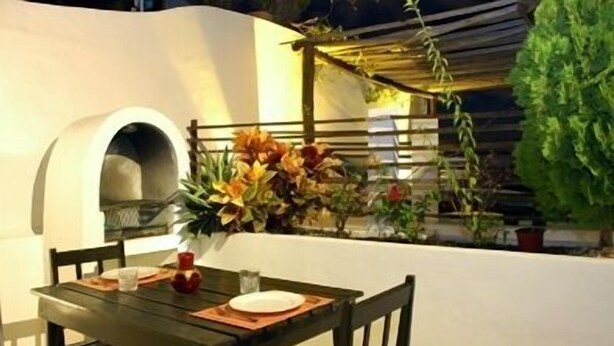 An outdoor dining area with a table set for two, a pizza oven, and potted plants. - Charming Penthouse, FREE INTERNET, CABLE and SAFE DEPOSIT BOX (Playa del Carmen)