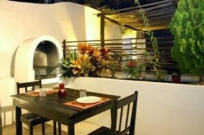An outdoor dining area with a table set for two, a pizza oven, and potted plants. - Charming Penthouse, FREE INTERNET, CABLE and SAFE DEPOSIT BOX (Playa del Carmen)