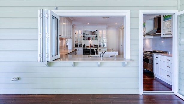 Una cocina moderna con armarios blancos, horno empotrado y una isla grande con fregadero.