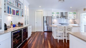 Una cocina moderna con armarios blancos, un enfriador de vino integrado y un refrigerador de acero inoxidable.