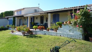 Ein Haus mit überdachter Veranda, Topfpflanzen und Rasen.