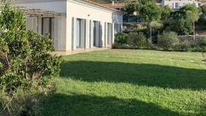 Eine Villa mit Ziegeldach, einem gepflegten Rasen und einem Bergpanorama im Hintergrund.