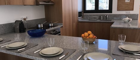 A modern kitchen with granite countertops, wooden cabinets, and a large window.