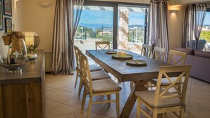 Zona pranzo con tavolo imbandito per quattro, sedie in legno, vista attraverso una porta in vetro e parete in pietra.