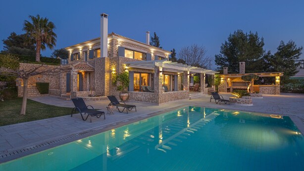 Una villa in pietra con piscina, area salotto esterna e camino.