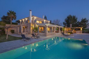 Una villa de piedra con piscina, mobiliario de exterior y chimenea.