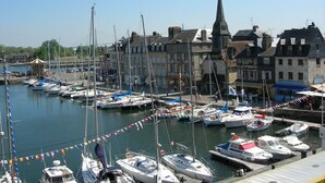 A marina with various boats docked, surrounded by historic buildings and a prominent church steeple. - PRIME VIEW on OLD HARBOUR. Refurbished. Wifi, GARAGE on option, Cleaning +linen  (Honfleur)