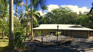 A building with a flat roof, surrounded by palm trees and other vegetation. - Spacious home in a lush green piece of paradise (Pahoa)
