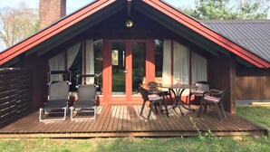 A wooden deck with outdoor furniture, a covered patio, and a brick chimney. - Year-round relaxation in a Danish holiday home with a fireplace in Gartow am See  (Gartow)