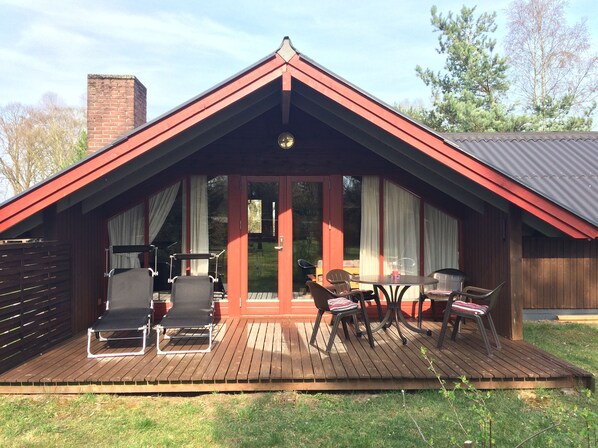 A wooden deck with outdoor furniture, a covered patio, and a brick chimney. - Year-round relaxation in a Danish holiday home with a fireplace in Gartow am See  (Gartow)