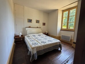 A bedroom with a bed, bedside tables, a window, and a radiator.