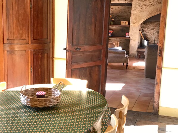 A wooden dining table with a green polka dot tablecloth, a wicker basket with a red lid, and a chair. - Gîte des Chaises Basses - Typical house in Corrèze in absolute calm (Orgnac-Sur-Vézère)