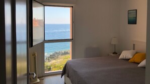 Ein Schlafzimmer mit einem großen Fenster und Blick auf den Ozean.
