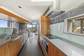 A modern kitchen with a stone backsplash, stainless steel appliances, and a view of the outdoors.