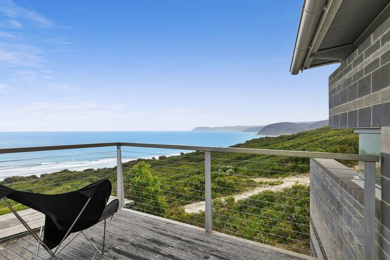 A balcony with a view of the ocean and hills.