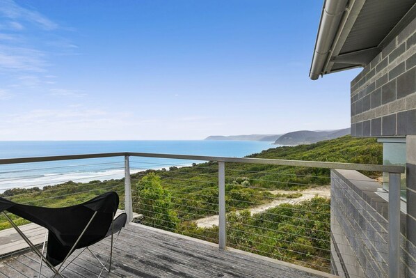 A balcony with a view of the ocean and hills.