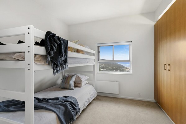 A bunk bed room with a window and a wardrobe.