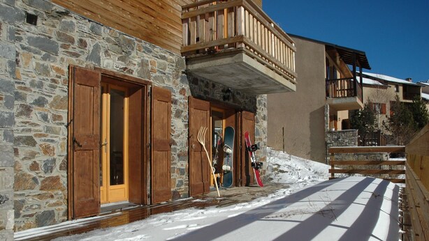 A stone building with wooden doors and a balcony.
