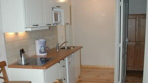 A compact kitchen with white cabinets, a microwave, and a coffee maker on the countertop.
