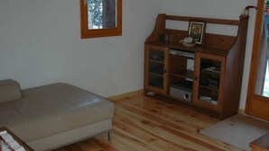 A room with a wooden floor, a sofa, a cabinet with glass doors, and a wall-mounted decoration.