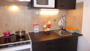 A kitchen with a stove, microwave, sink, and a bowl of oranges. - "Côté Jardin" .... absolute calm in the center of Cannes ... with garage (Cannes)