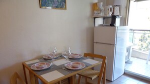 A dining area with a table set for four, four chairs, and a refrigerator in the background. - "Côté Jardin" .... absolute calm in the center of Cannes ... with garage (Cannes)
