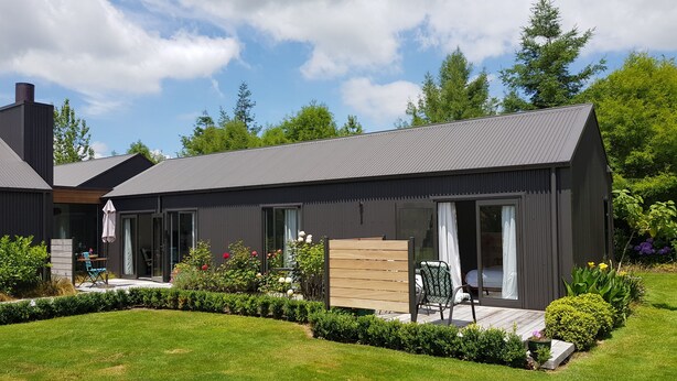Une maison moderne à l’extérieur sombre, dotée de grandes fenêtres et d’un jardin bien entretenu.
