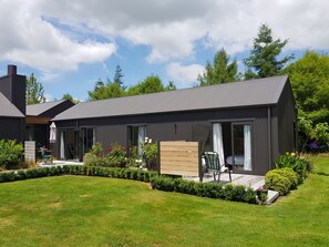 A modern house with a dark exterior, large windows, and a well-maintained garden. - Watershed  - Lake Karapiro (Lake Karapiro)