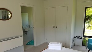 Une chambre à coucher comprenant un lit, une armoire, un miroir et une fenêtre donnant sur un paysage verdoyant.