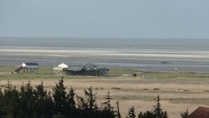 A coastal area with two buildings, one elevated on stilts and another on a lower foundation, both with visible signage. - Vacation apartment with a view of the North Sea (Schleswig Holstein)