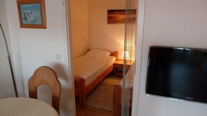 A bedroom with a bed, a TV, a chair, and a painting on the wall. - Vacation apartment with a view of the North Sea (Schleswig Holstein)