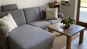 Uma sala de estar moderna com um sofá seccional cinza, uma mesa de centro de madeira e um quadro de uma paisagem na parede.